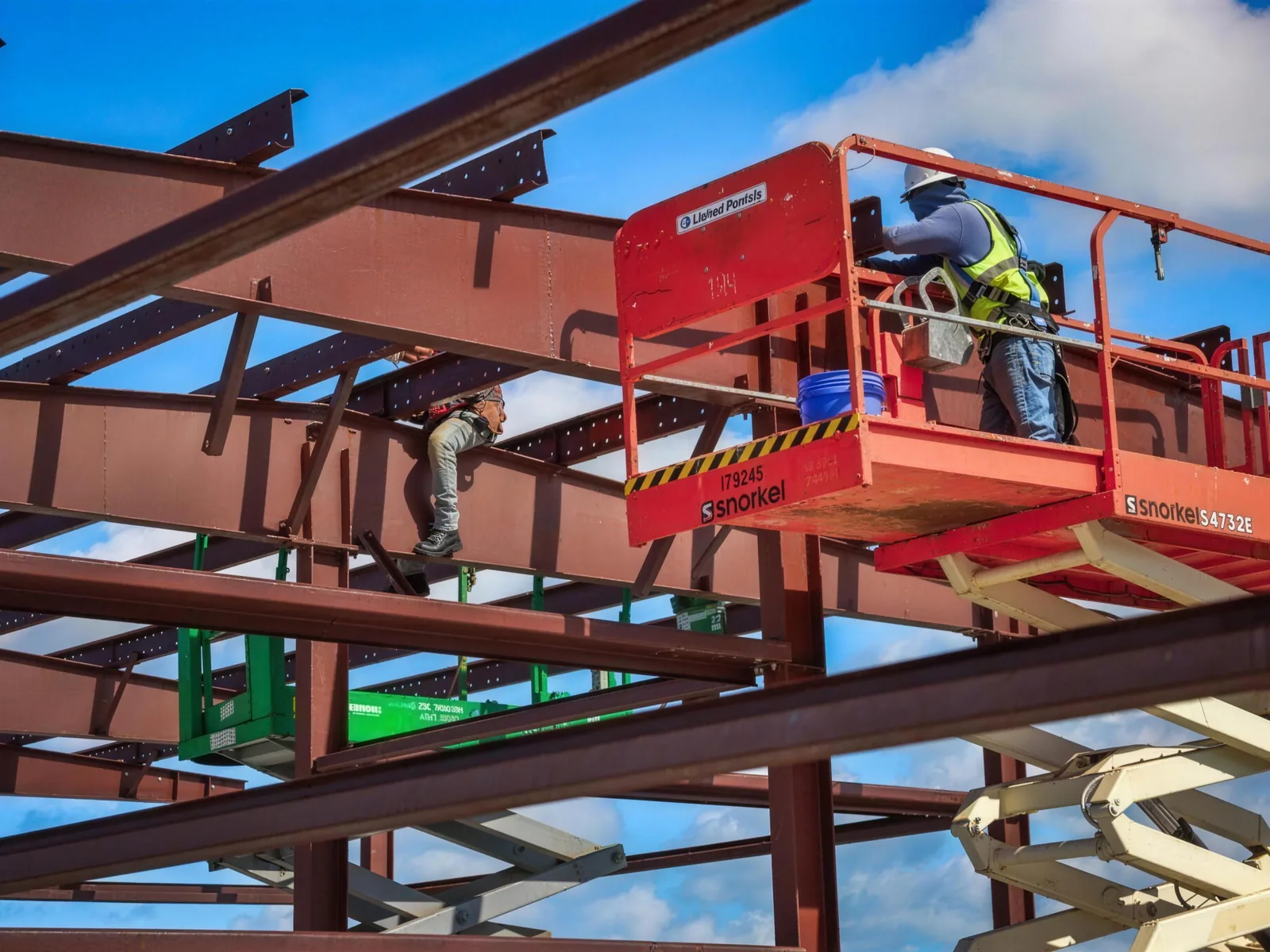 Crew setting steel framing members from a lift during a building erection