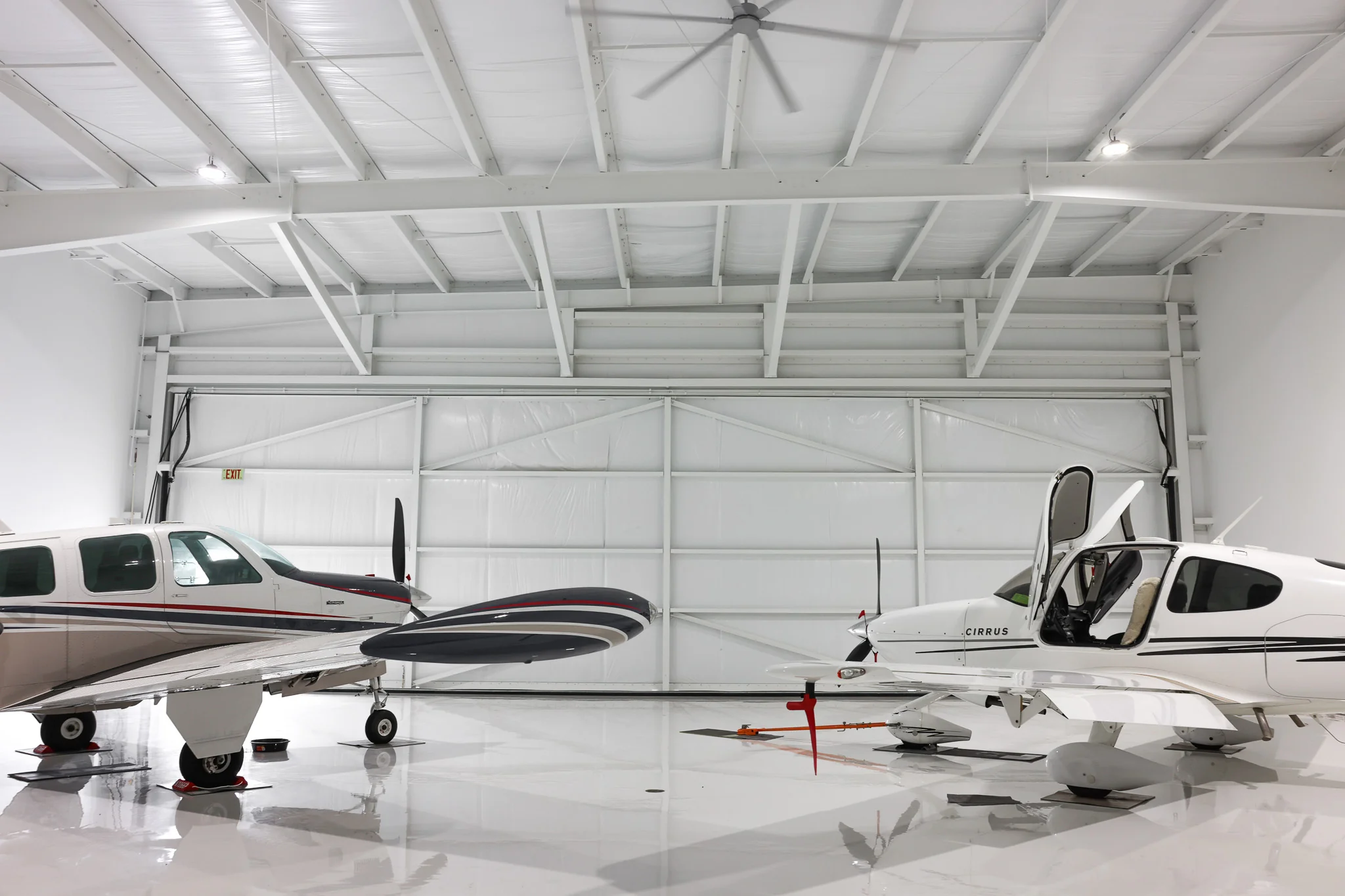 Aircraft facing bifold hangar door with clear-span steel framing