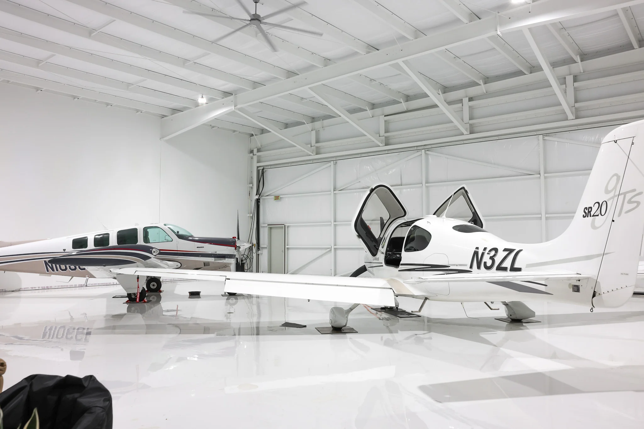 Two aircraft stored in hangar with roll-up door visible