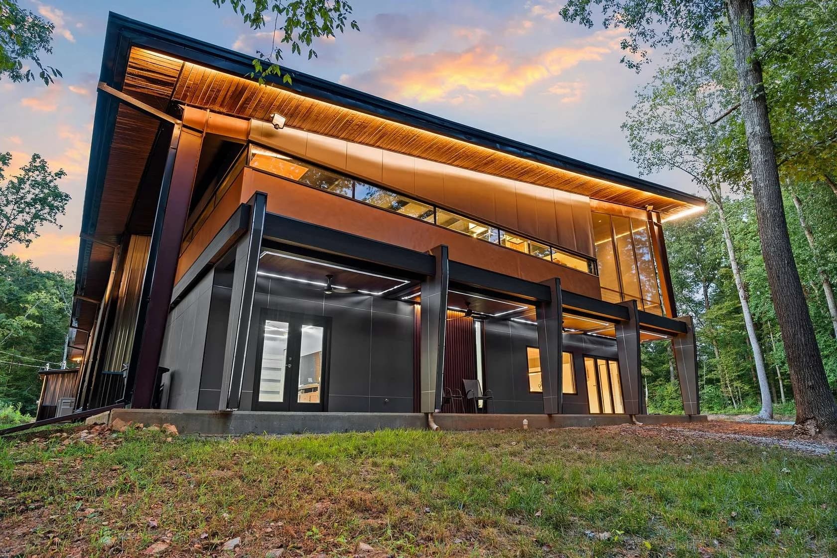 Modern steel-framed barndominium with wood accents at sunset